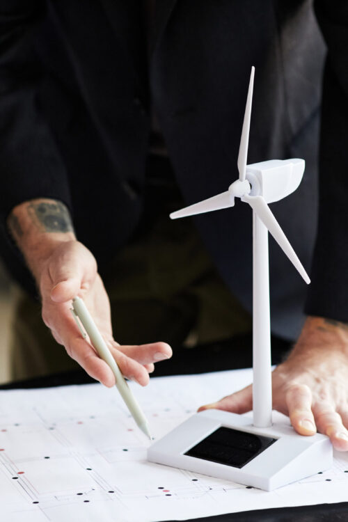 Close-up of engineer examining blueprint at table with windmill mockup